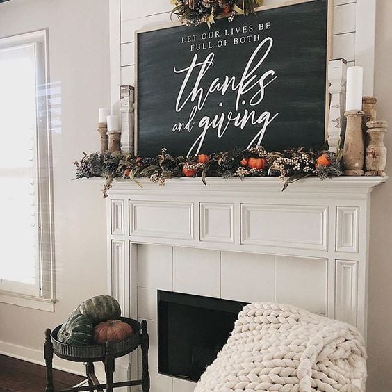 mantel with a large sign, pumpkins, and greenery