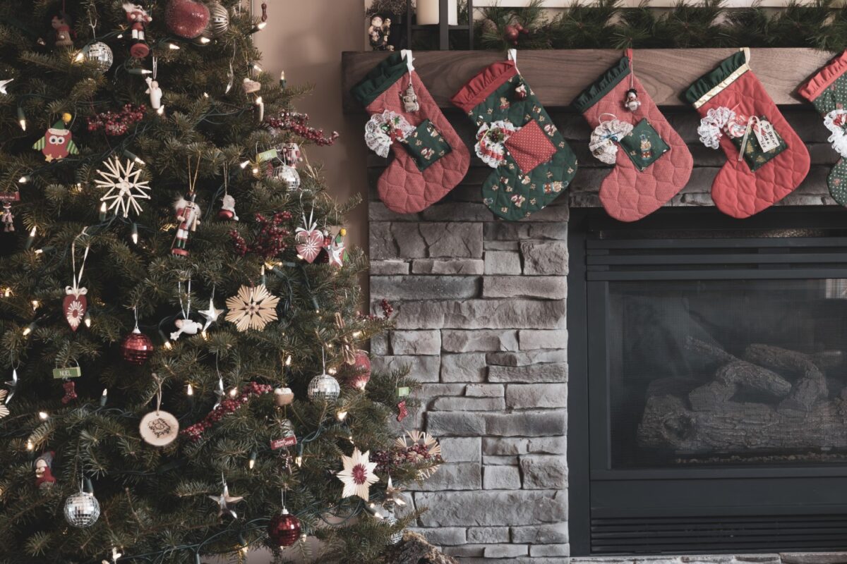 Festive themed gray fireplace, with stockings hanging over it next to a Christmas tree.