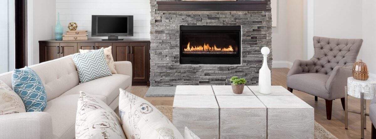 Gray stacked stone fireplace with a large mirror at the top of it.