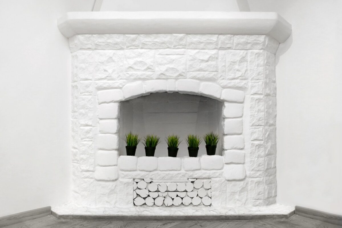 White stone fireplace with small plants inside.